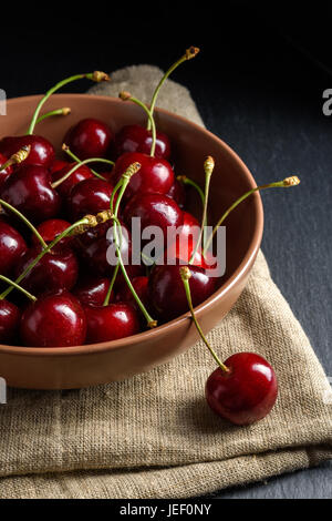 Sweet cherry in brown bowl on black slate stone Stock Photo