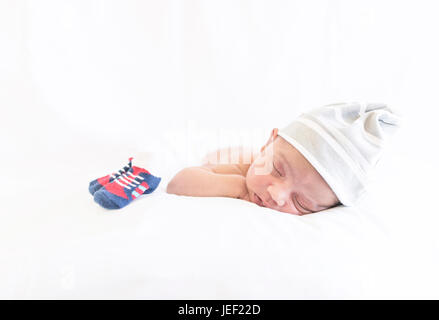 Model released photograph of a newborn baby with a cap sleeping on his tummy Stock Photo