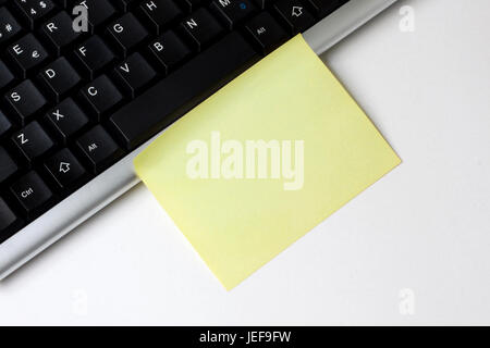 Empty Sticky Note and Keyboard on the White Desk Stock Photo
