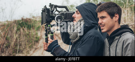 Behind the scene. Cameraman and film director shooting film scene on outdoor location Stock Photo