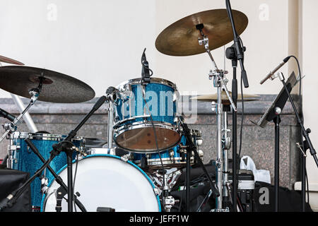 blue drum set and cymbals standing on outdoor stage against wall background Stock Photo