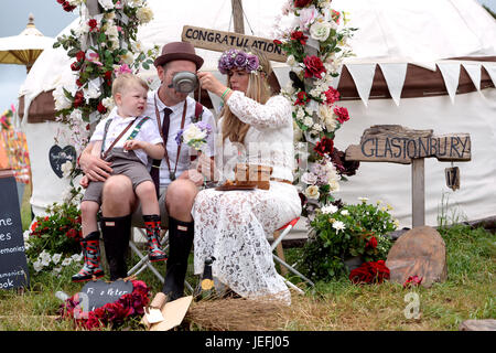 Fi Sexton, 32 and Peter Howe, 38, both from London accompanied by son Thomas Howe, 2 take part in a Handfasting wedding ceremony. The ceremony involved tying their hands together with bonds, Jumping a broom and Eating cake and drinking ale together at Glastonbury Festival, at Worthy Farm in Somerset. Stock Photo