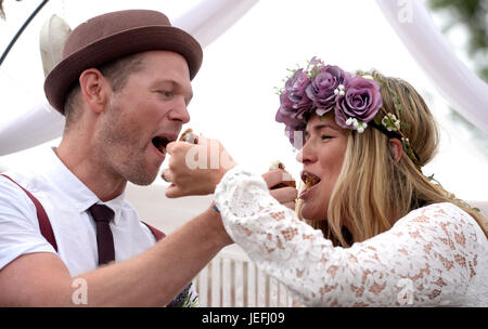 Fi Sexton, 32 and Peter Howe, 38, both from London accompanied by son Thomas Howe, 2 take part in a Handfasting wedding ceremony. The ceremony involved tying their hands together with bonds, Jumping a broom and Eating cake and drinking ale together at Glastonbury Festival, at Worthy Farm in Somerset. Stock Photo