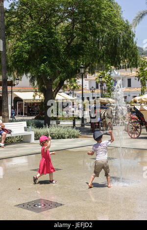 Children, toddlers, playing with water fountains on hot day in spanish village, Mijas, Costa del Sol, Spain. Stock Photo