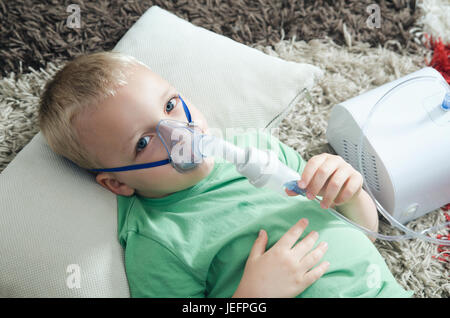 Boy making inhalation with nebulizer at home. child asthma inhaler inhalation nebulizer steam sick cough concept Stock Photo