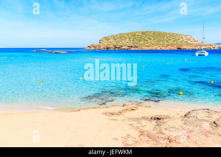 Beautiful turquoise water of Cala Comte bay and catamaran boat on sea in background, Ibiza island, Spain Stock Photo