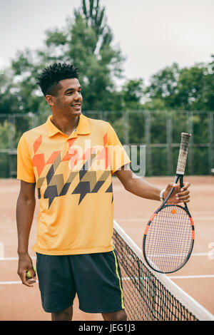 Portrait of a smiling tennis player with racket on tennis court Stock Photo