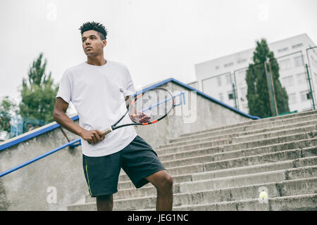 Handsome young man in polo shirt holding tennis racket Stock Photo