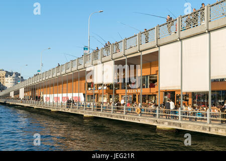 Istanbul, Turkey - April 25, 2017: Galata Bridge with traditional fish restaurants and fishermen fishing Stock Photo
