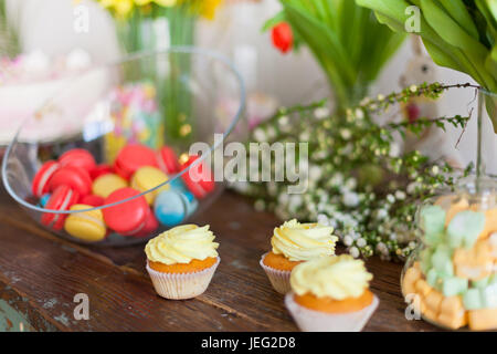Bright macaroons and cupcakes on a wooden table. Indoors natural light shot with small depth of field Stock Photo