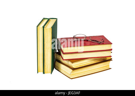 A pile of hard-bound books and reading glasses lie on a light background Stock Photo