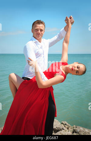 Man and woman posing in dance by the sea on a bright sunny day. Stock Photo