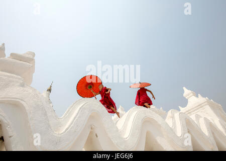 Monks with umbrella in Hsinbyume Pagoda Temple in Mandalay Myanmar Mingon Sagaing region White temple pagoda Myanmar Stock Photo