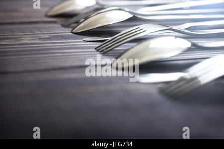 Steel spoons and forks in a row on a table close-up. Stock Photo
