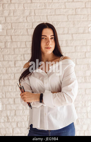 Beautiful young beautician woman holding set of make up brushes. Stock Photo