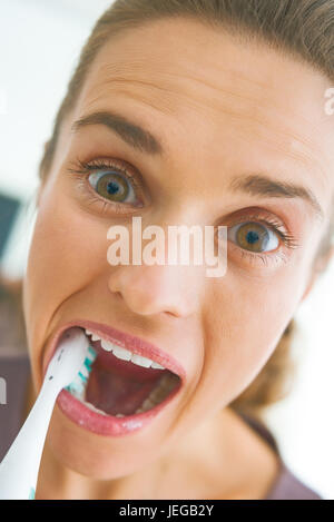Funny portrait of young woman intensively brushing teeth Stock Photo