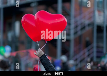 Two LED balloons in the form of scarlet burning hearts in the evening in girl's hand. For a romantic background, for example, in the day of Valentine's Day Stock Photo