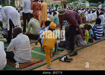 June 25, 2017 - Juba, Jubek, South Sudan - A father and his son take off their shoes as they join thousands in the Malkei neighborhood of Juba, South Sudan and the rest of the Muslim world Sunday in the beginning of Eid al-Fatr, the celebration marking the end of the Muslim holy month of Ramadan. Roughly half the population of South Sudan is Muslim, a legacy of its long domination by the Arab-controlled northern Sudan, which ended in 2011, when South Sudan became the world's newest nation. The country has been in a state of civil war for the past three years, leaving millions of civilians disp Stock Photo