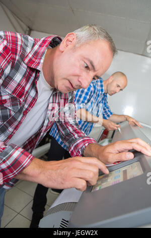 man working in printing house programming printer machine Stock Photo