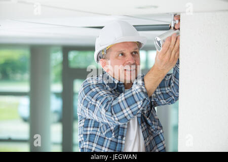 mature male technician on stepladder fitting cctv camera Stock Photo
