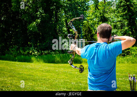 Man in blue shirt shooting his bow an arrow at the range Stock Photo
