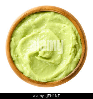 Avocado cream in wooden bowl. Alligator pear, the fruit of the Persea americana tree. Light green paste of mashed avocados and lemon juice. Photo. Stock Photo