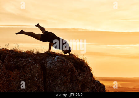 Silhouette of man doing yoga meditation against beautiful sky with clouds. Stock Photo