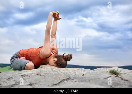 Attractive woman making yoga exercise on the big stone against beautiful river. Stock Photo