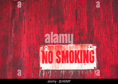 A no smoking sign on a painted red wooden wall; Orion, Alberta, Canada Stock Photo