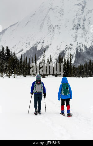 Two women snowshoeing in the mountains, East of Field; British Columbia, Canada Stock Photo