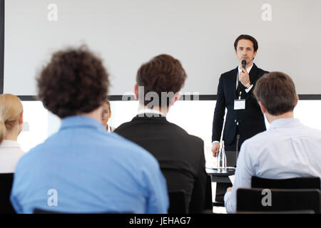 Speaker at business conference near white screen and audience Stock Photo