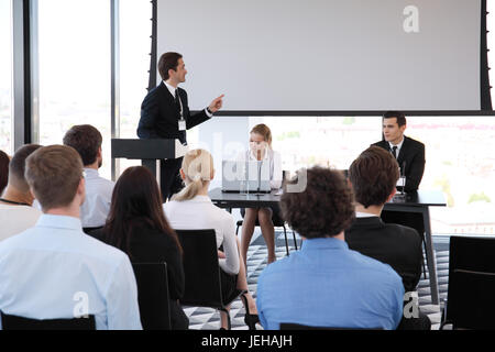 Speaker at business conference near white screen and audience Stock Photo