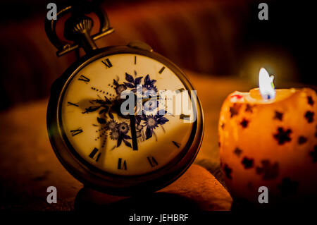old bronze watch beside candle Stock Photo