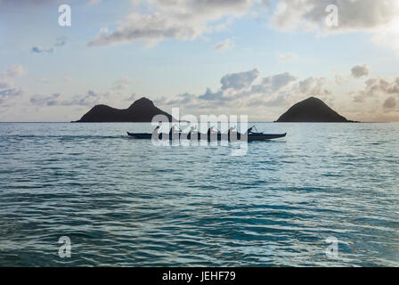 A group of canoers paddling through Lanikai Beach in a canoe in front of the Mokulua islands, Kailua; Honolulu, Oahu, Hawaii, United States of America Stock Photo