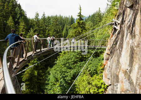 Tourists walking on the Capilano Suspension Bridge; Vancouver, British Columbia, Canada Stock Photo