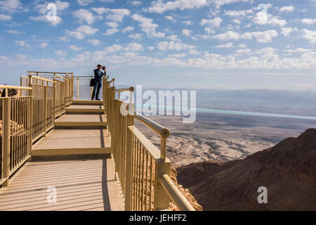 A tourist stands at the end of a lookout with a view of the Dead Sea region and the desert; South District, Israel Stock Photo