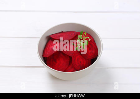 bowl of thin beetroot slices on white wooden background Stock Photo