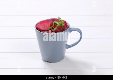 cup of thin beetroot slices on white wooden background Stock Photo