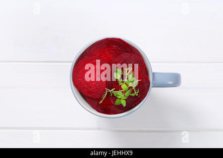 cup of thin beetroot slices on white wooden background Stock Photo