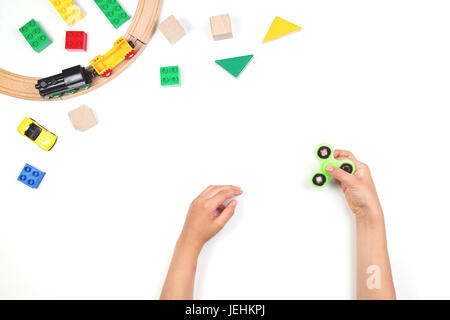 Kids hands playing with fidget spinner toy. Many colorful toys on white background. Stock Photo