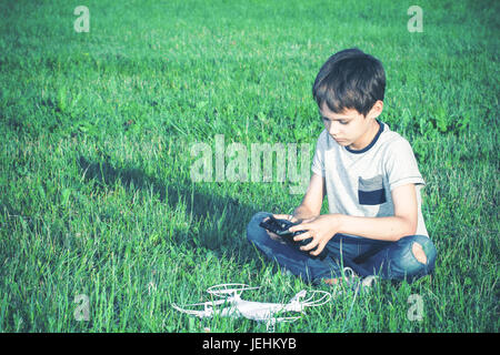 Boy with drone sitting on the grass. Stock Photo