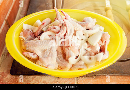 Chicken wings prepared for frying, grilling, laying in a big yellow bowl on the stove. Stock Photo