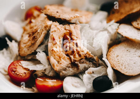 salad with salmon, freshness, Ruskson and black olives on white plate. Lifestyle healthy eating Food photo concept. Fried fish in focus. Stock Photo