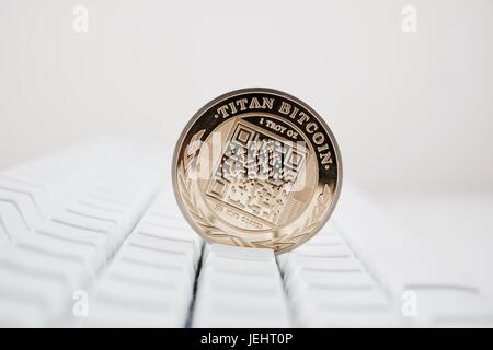 Digital currency physical gold titan bitcoin coin on white computer keyboard. Stock Photo