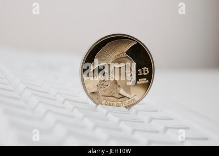 Digital currency physical gold titan bitcoin on white computer keyboard. Stock Photo