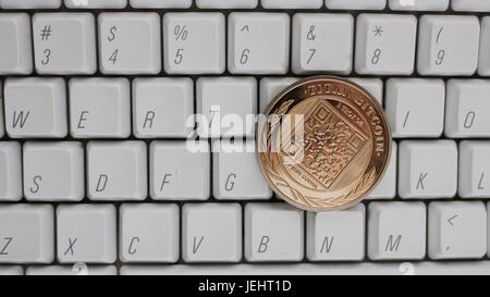 Digital currency physical gold titan bitcoin on white computer keyboard. Stock Photo