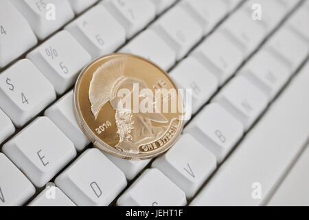 Digital currency physical gold titan bitcoin on white computer keyboard. Stock Photo