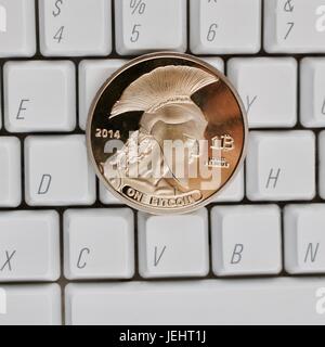 Digital currency physical gold titan bitcoin coin on white computer keyboard. Stock Photo