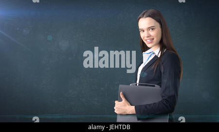 Young beautiful businesswoman portrait with gray briefcase, dark background Stock Photo