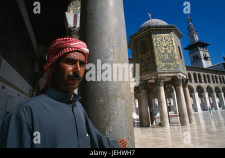 Syria, South, Damascus, Pilgrim at the Umayyad Mosque with the Dome of the Treasury and the Minaret of the Bride in the background. Stock Photo